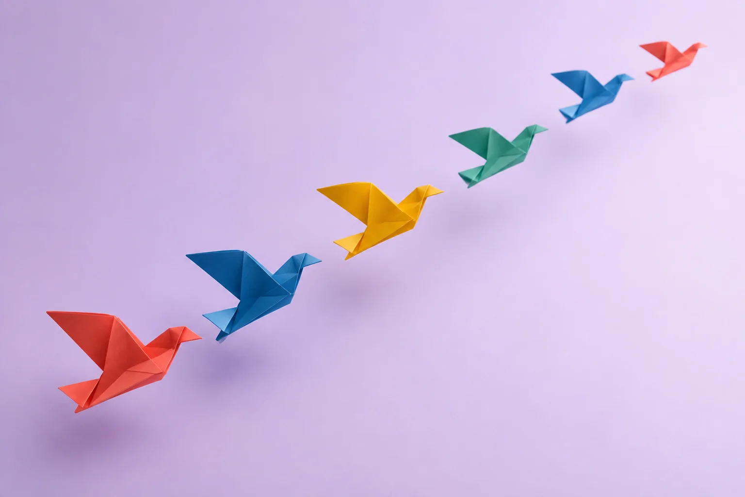 Colorful folded-paper forms suspended in a coordinated upward arc.